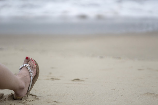 女性光脚与拖鞋在海滩上图片下载