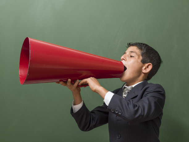 小男孩在绿色的黑板前用扩音器大喊图片下载