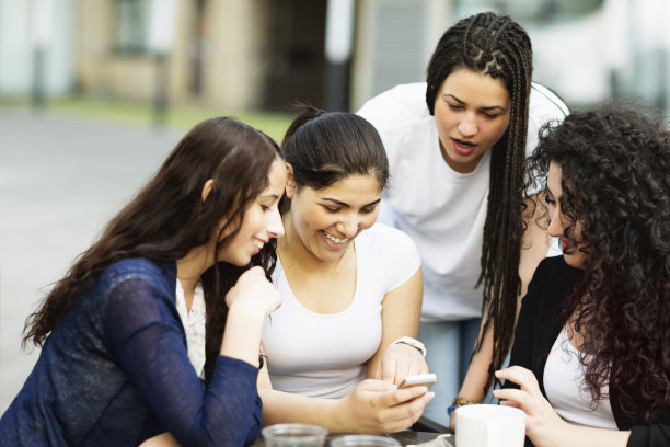 四个年轻女性用手机发短信，玩得开心图片下载