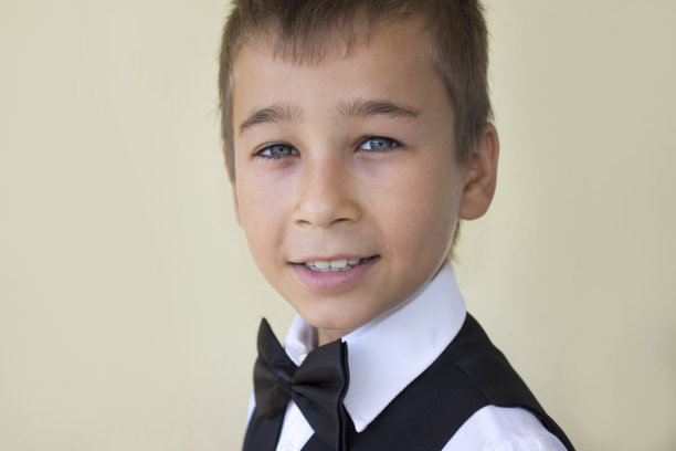 穿西装的小男孩在彩色背景下看着相机图片下载