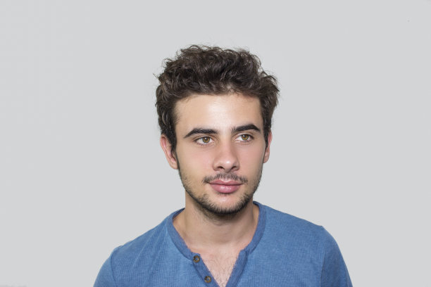 一个十几岁的男孩在灰色背景前的肖像图片下载