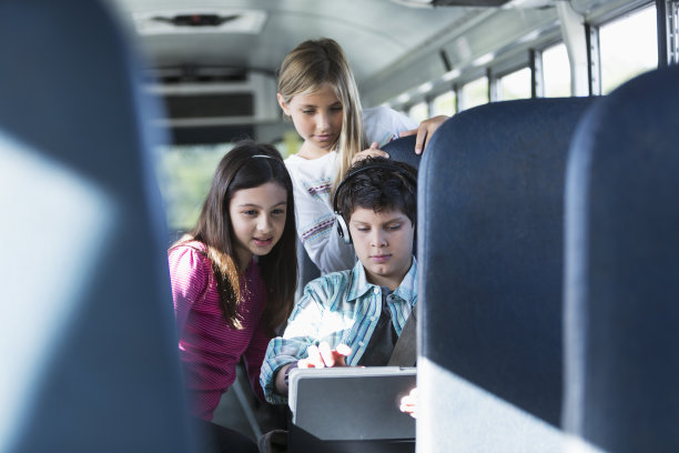 乘坐带有平板电脑的校车上的孩子们图片下载