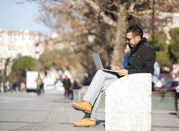 英俊的年轻人在户外使用笔记本电脑图片下载