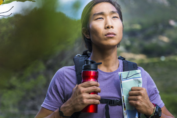 细心的徒步旅行者拿着水瓶和地图在森林里图片下载