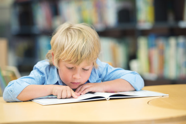 小男孩坐在桌子旁看书图片下载