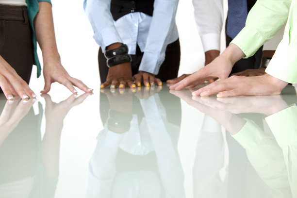 商业:一群不同的专业人士，双手放在反光桌上。图片下载