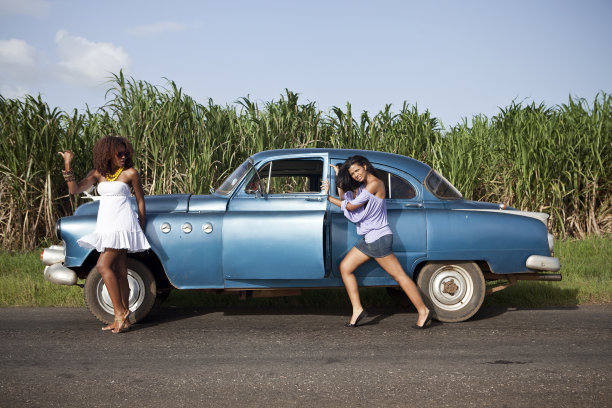 两个女人在她们的老式汽车旁搭车图片下载