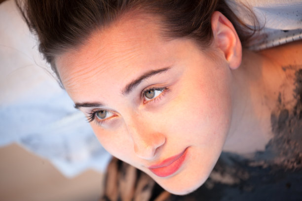 漂亮的黑发女孩享受水疗泥浆处理在傍晚的太阳图片下载