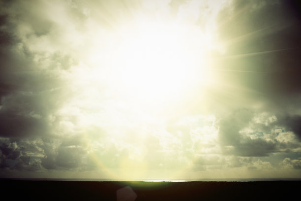 明亮的太阳被海面上的云层稍稍遮蔽图片下载