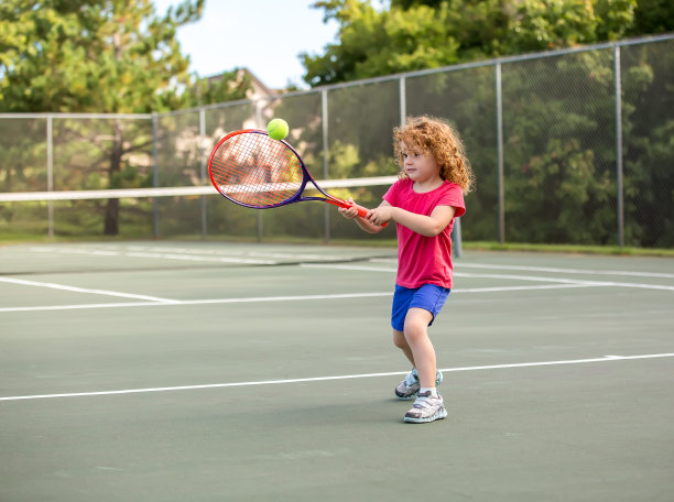 年轻女孩与卷红头发打网球图片下载