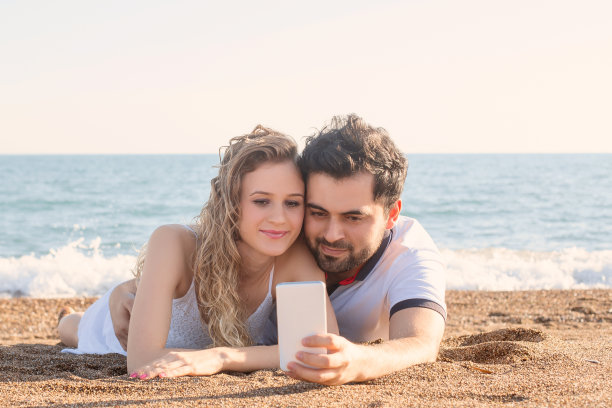 一对年轻情侣在海滩上自拍图片下载