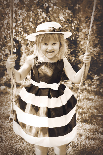 可爱的小姑娘坐在秋千上。图片下载