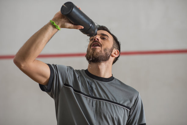 精疲力竭的运动员从运动瓶里喝水。图片下载