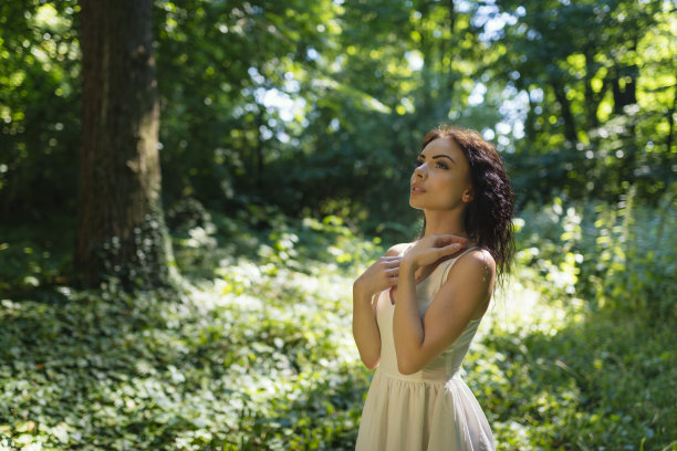 一个年轻女子在阳光明媚的公园里感受自由图片下载