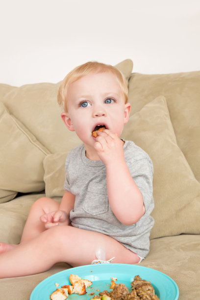 蹒跚学步的小男孩在沙发上吃东西图片下载