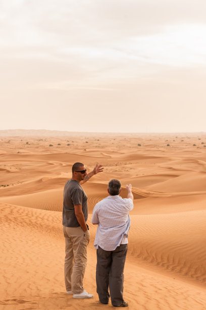 在沙丘上观看风景的阿拉伯男人和白人男人图片下载