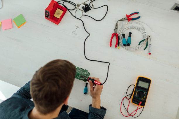 在他的技术办公室里焊接电路板的人。图片下载