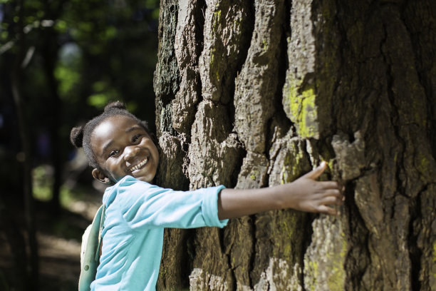 一个非洲小孩抱着一棵树，对着镜头微笑图片下载