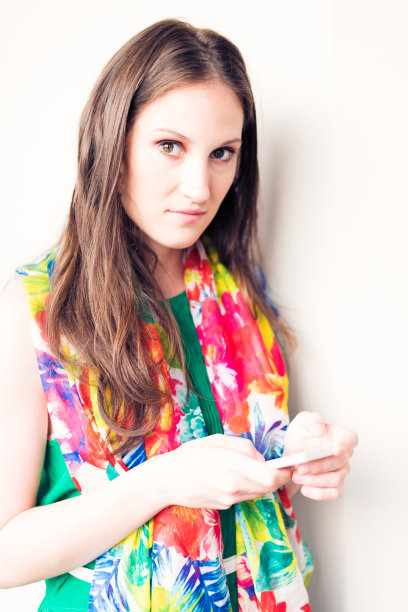 一个穿着鲜艳裙子的女人在用她的智能手机图片下载