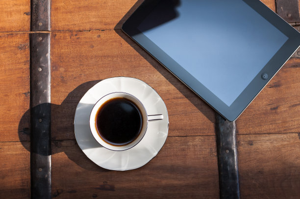 咖啡杯和iPad平板电脑放在咖啡桌上图片下载
