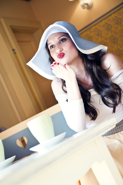 戴着大帽子微笑的年轻女子飞吻图片下载