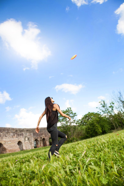 年轻女子向公园投掷飞盘图片下载
