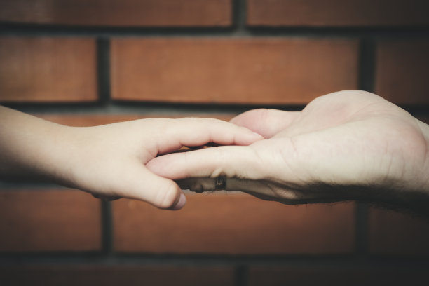 父子牵手站在砖墙前图片下载