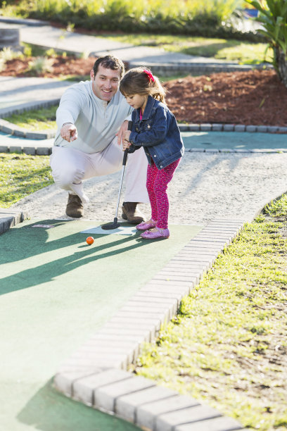 小女孩和爸爸在打迷你高尔夫图片下载