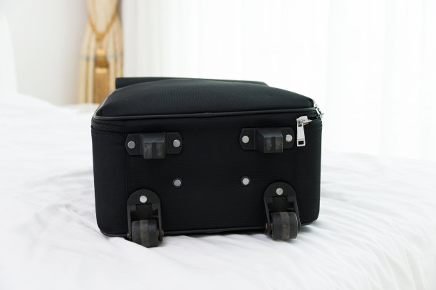 单只黑色行李箱放在酒店床上图片下载