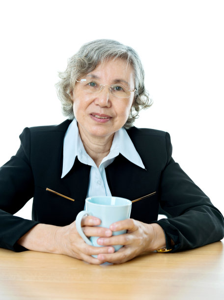 资深女商人拿着杯子在办公桌前图片下载