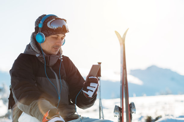 放松的滑雪者戴着耳机在山顶图片下载