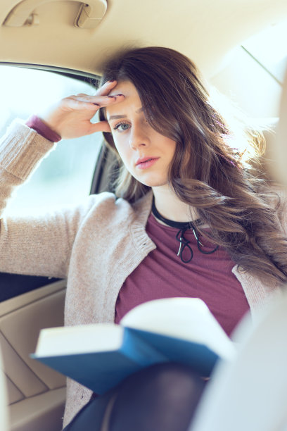 漂亮的女孩在轿车后座看书图片下载