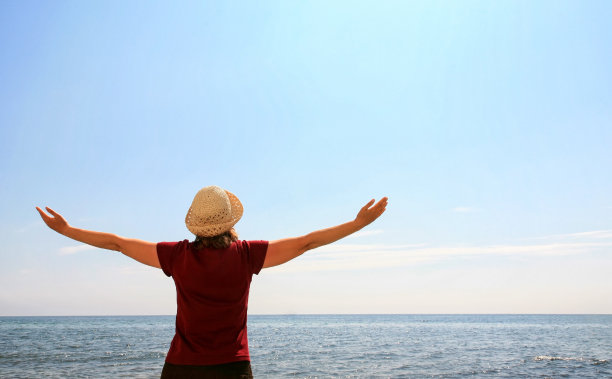 在海滩上举起手臂的女人图片下载