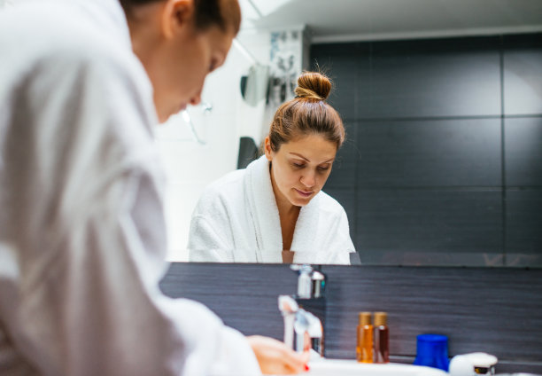 一个穿着浴袍的女人在浴室里洗脸图片下载