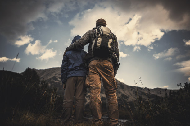 夕阳西下时，父亲和儿子在山上徒步旅行图片下载