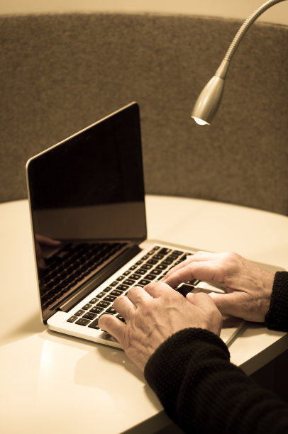 男性双手在带台灯的办公桌上使用笔记本电脑图片下载