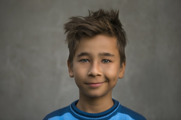 灰色的墙上挂着一个微笑的小男孩的肖像图片下载