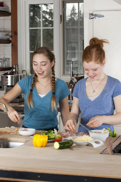 青少年用蔬菜和火腿做披萨图片下载