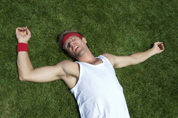 疲惫的运动员躺在草地上昏倒图片下载