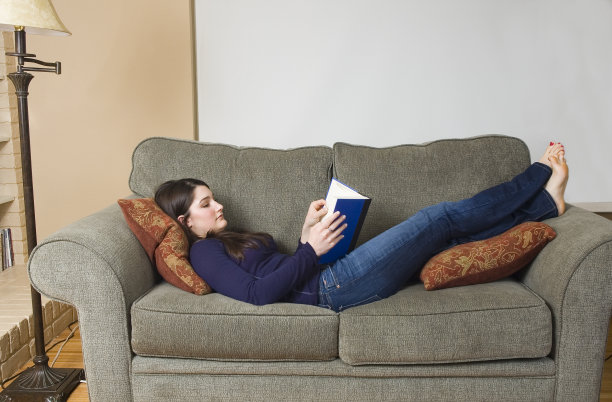 坐在沙发上看书的少女图片下载