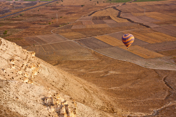在收获过的田地上空放飞热气球图片下载