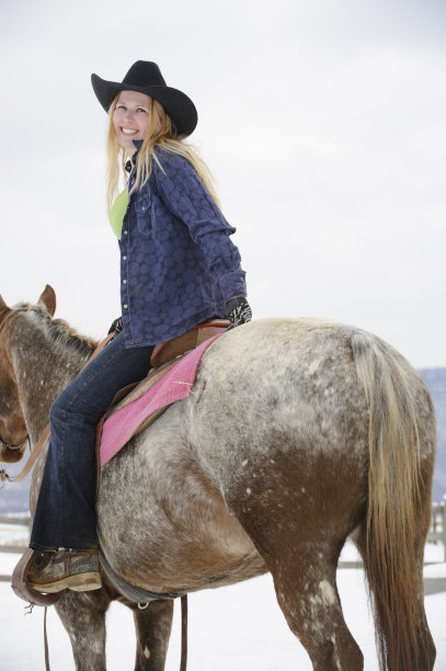 金发女人微笑骑阿帕卢萨马在冬天，后视图图片下载