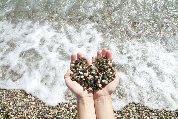 沙滩上女人手里的鹅卵石图片下载