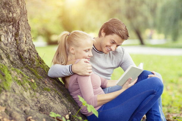 一对年轻夫妇在公园里看书图片下载