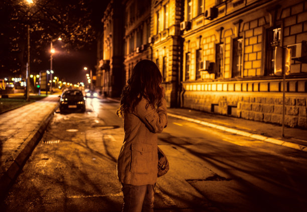 年轻女子晚上在城市里站着等出租车图片下载