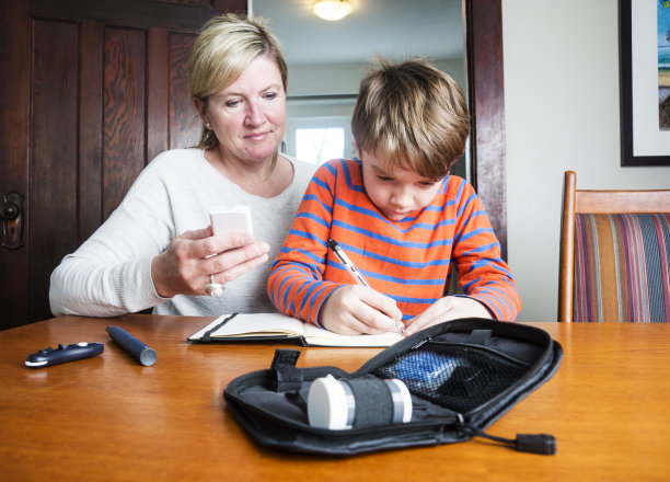 青少年糖尿病患者和他的母亲记录他的水平素材图片