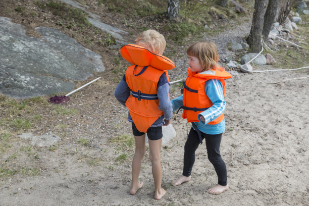 光着脚的小男孩和小女孩穿着亮橙色的救生衣图片下载