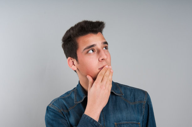 一个在灰色背景下思考的年轻人图片下载