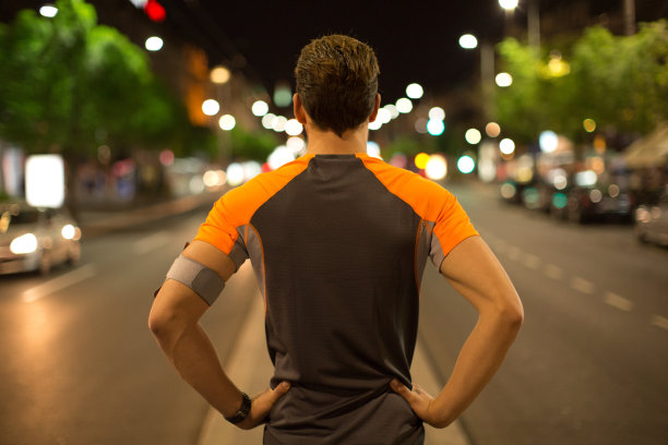 一个年轻人在晚上慢跑穿过这座城市。图片下载