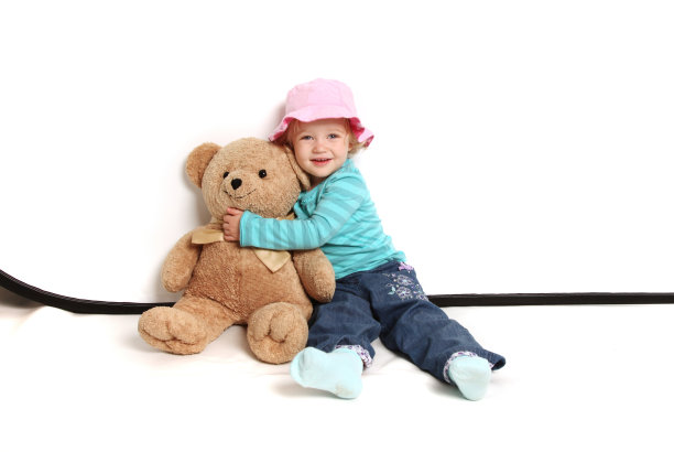 小女孩戴着一顶粉红色的帽子，抱着泰迪熊图片下载